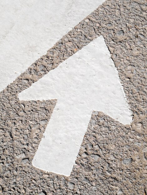 High angle of big white arrow on asphalt