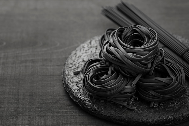 High angle of black tagliatelle on plate with spaghetti