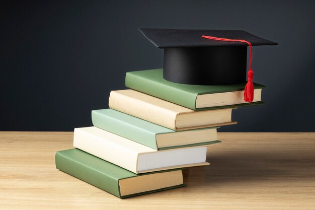 High angle of books and a graduation cap for education day