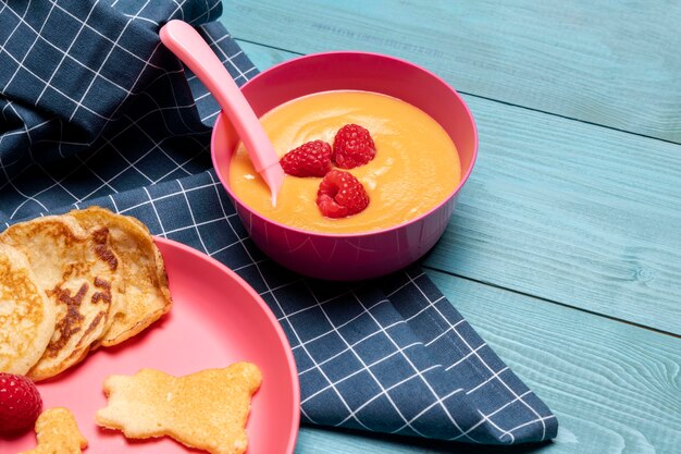 High angle of bowl with baby food and raspberries