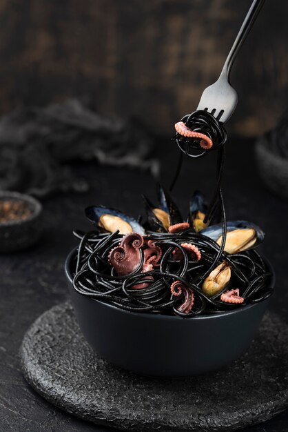 High angle of bowl with black spaghetti and squid