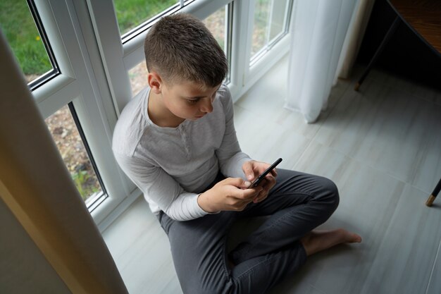Мальчик под высоким углом держит смартфон