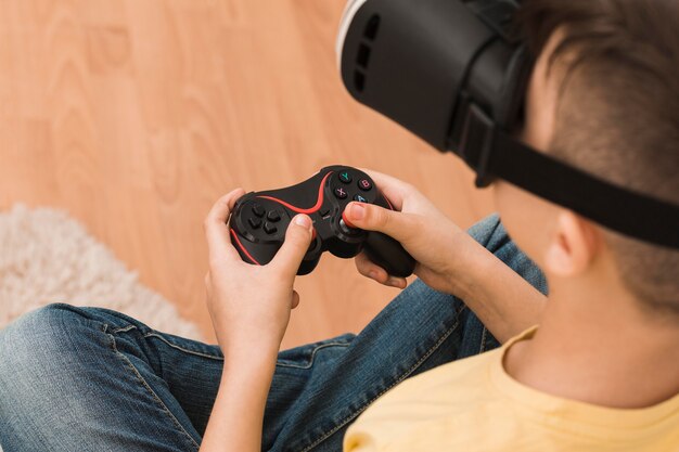 Высокий угол мальчика, играющего в видеоигры с гарнитурой виртуальной реальности