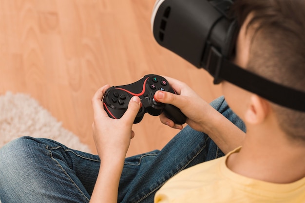 High angle of boy playing video games with virtual reality headset