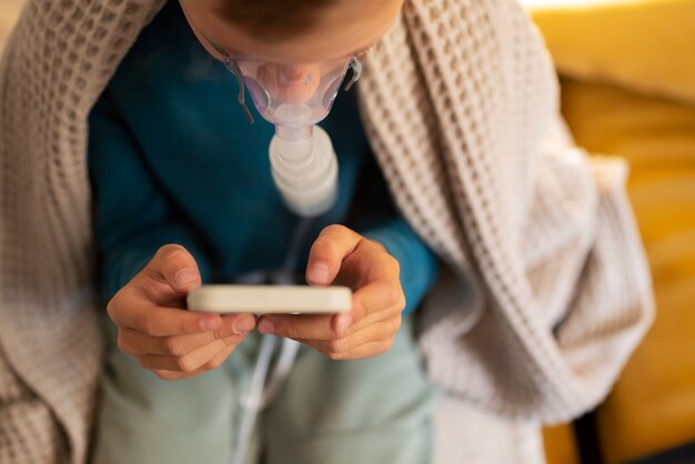 Free photo high angle boy using a nebulizer