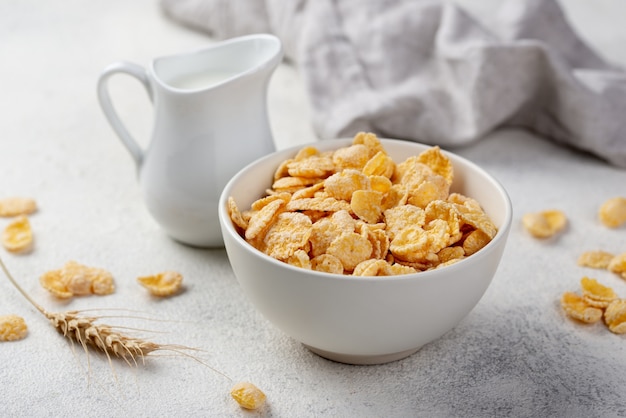 High angle of breakfast corn flakes in bowl with milk and wheat