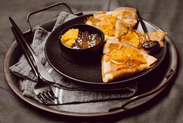 High angle of breakfast crepes on bed with jam