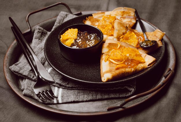 High angle of breakfast crepes on bed with jam