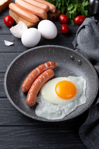 High angle of for breakfast egg and sausages in pan with tomatoes and herbs