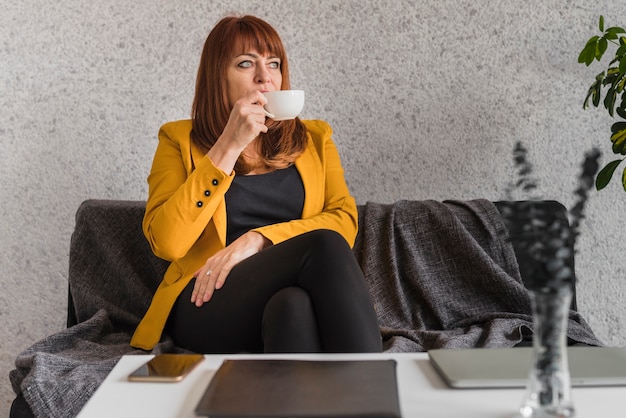 Free photo high angle business woman enjoying coffee