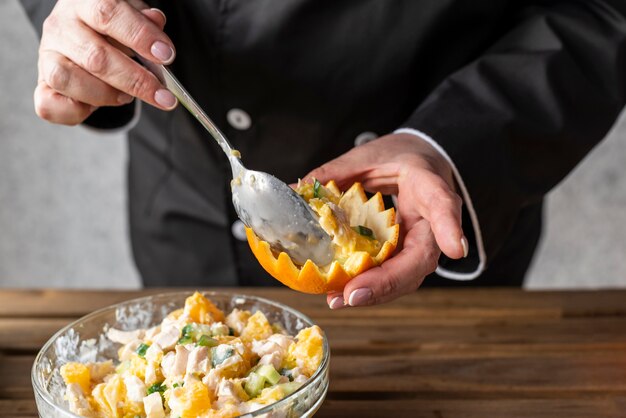 High angle of chef filling orange with dish