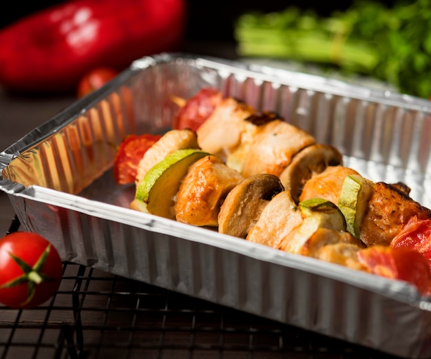 High angle chicken skewers on tray with red pepper and tomatoes