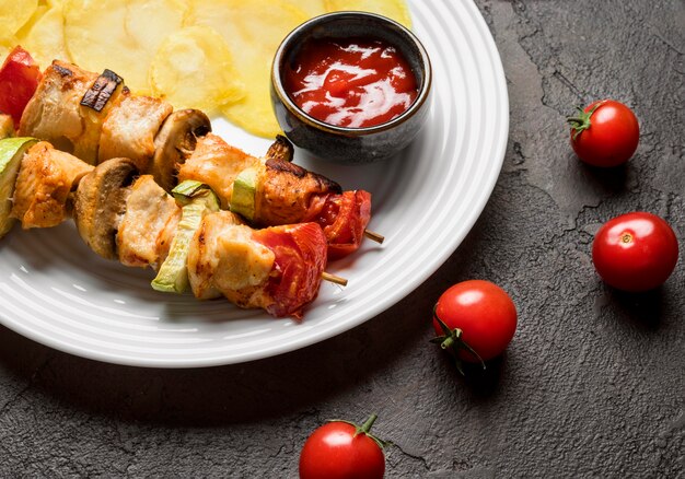 High angle chicken skewers with sauce and chips