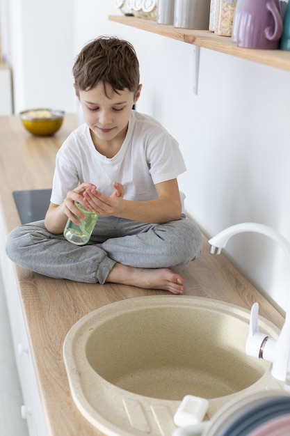 Free photo high angle of child using liquid soap