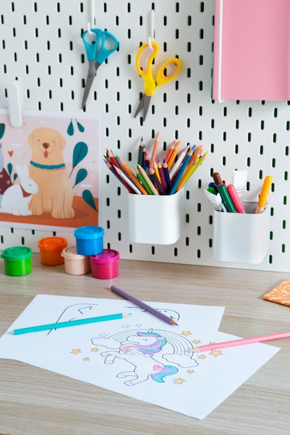 Детский стол с рисунками и карандашами под высоким углом
