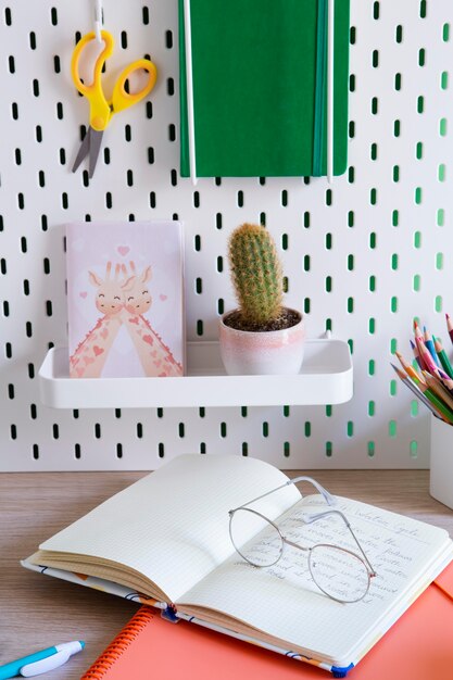 High angle of children's desk with glasses and notebook