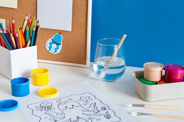 High angle of children's desk with paint and drawing