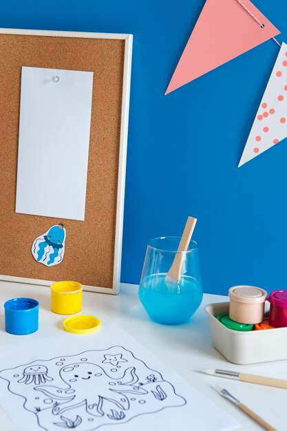 High angle of children's desk with paint and drawing