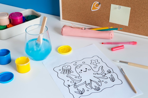 Free photo high angle of children's desk with paint and drawing