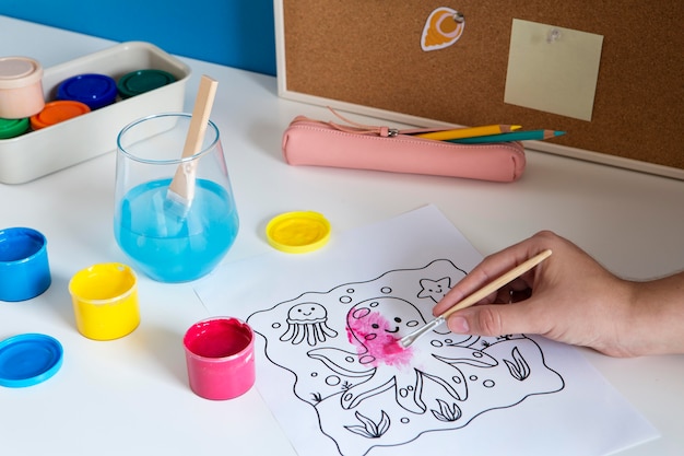 High angle of children's desk with paint and drawing