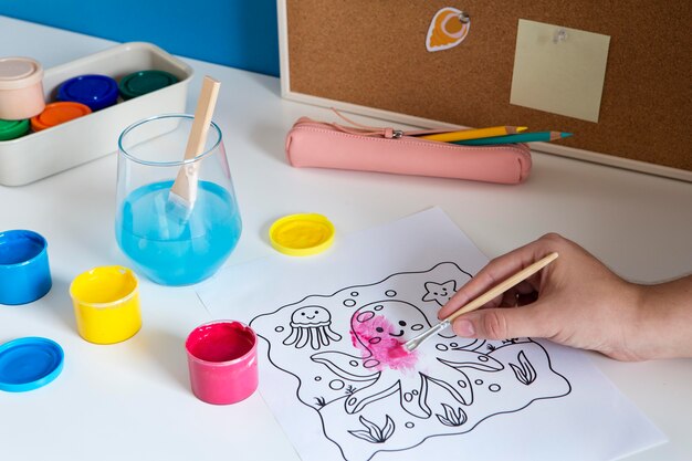 High angle of children's desk with paint and drawing