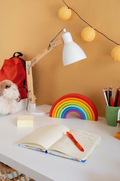 High angle of children's desk with rainbow and notebook