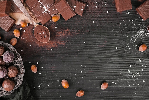 Foto gratuita barrette di cioccolato e cucchiaio dell'angolo alto con lo spazio della copia e della polvere di cacao