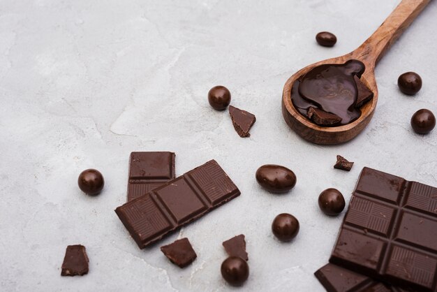 High angle chocolate bars and wooden spoon with chocolate syrup