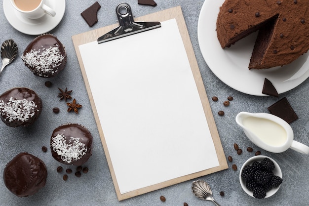 High angle of chocolate cake with notepad and other desserts