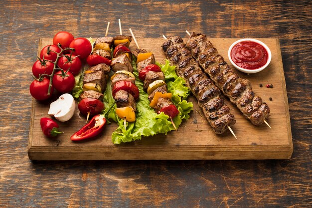 High angle of chopping board with delicious kebab and vegetables