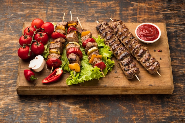 High angle of chopping board with delicious kebab and vegetables