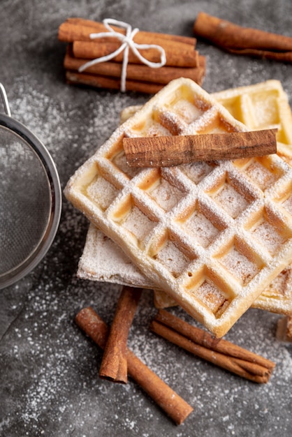 Free photo high angle of cinnamon sticks on sugar powdered waffles