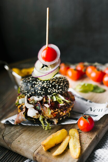 High angle close-up of black burger and fries on wooden board