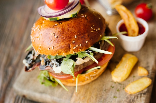 High angle close-up burger with fries on wooden board