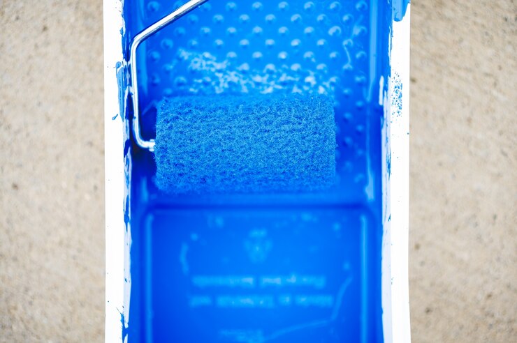 Free Photo high angle closeup shot of blue paint in a paint container with a brush
