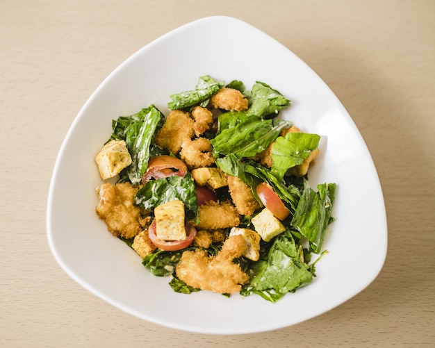 Free photo high angle closeup shot of a caesar salad in a white bowl