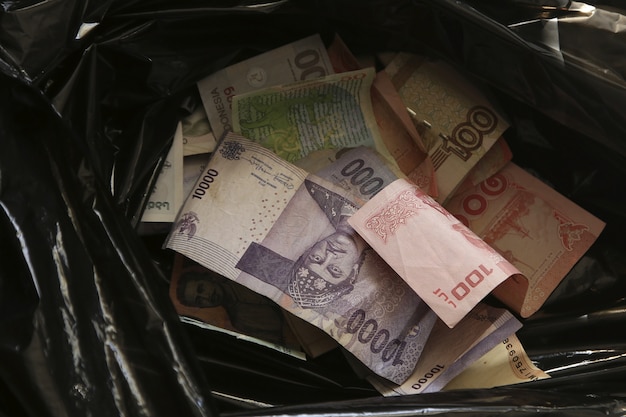 High angle closeup shot of cash money in a black trash bag