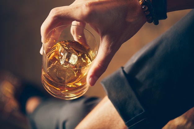 ウイスキーのグラスを持っている男性の高角度のクローズアップショット