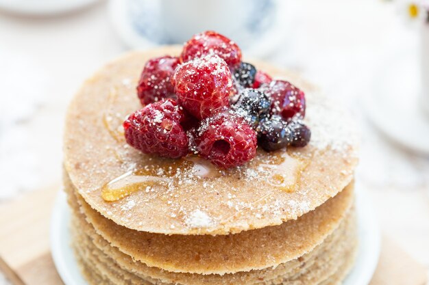 High angle closeup shot of raw vegan pancakes with honey and berries