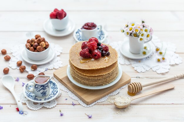 High angle closeup shot of raw vegan pancakes with honey and berries