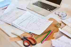 Free photo high angle of clothing line plans on table with laptop and scissors in atelier