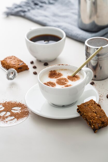 High angle of coffee cups with desserts and plate