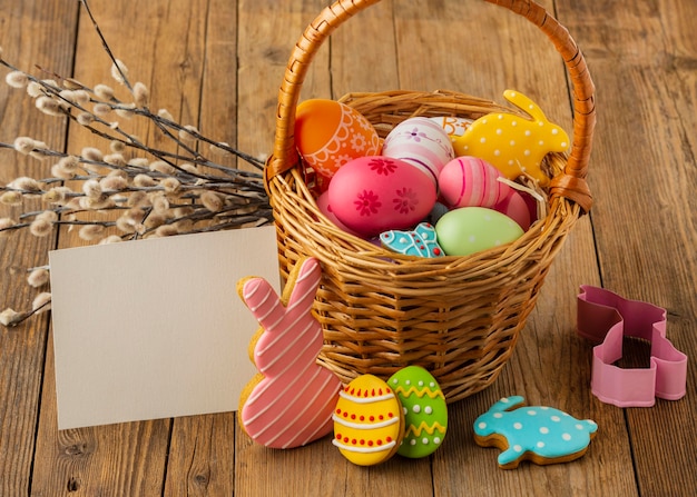 High angle of colorful easter eggs in basket with bunny and paper