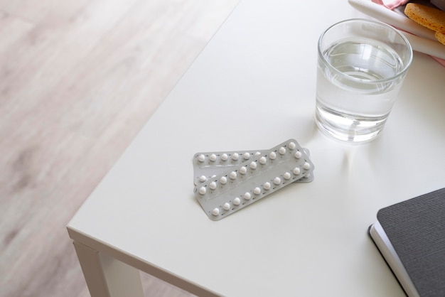 Free photo high angle contraceptive and water on table