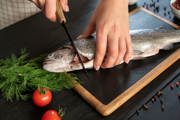 Foto gratuita cuoco ad alto angolo che pulisce il pesce in cucina