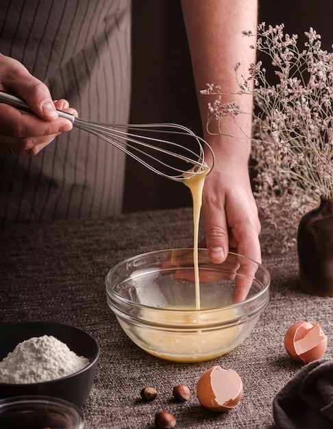 Free photo high angle of cook whisking eggs in bowl