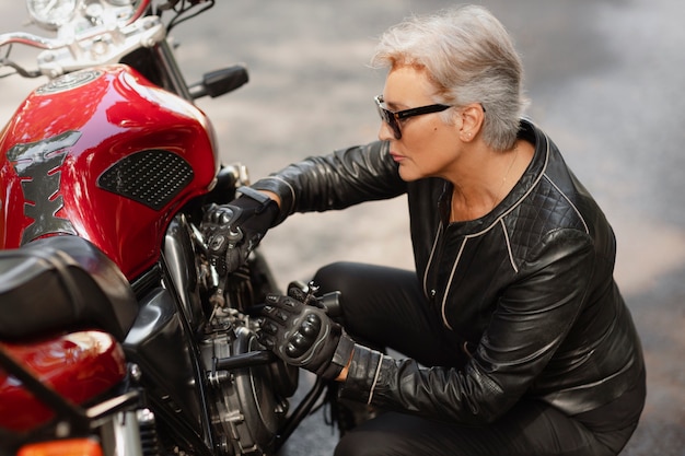 Foto gratuita donna anziana fresca dell'angolo alto con la motocicletta