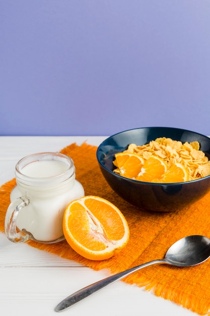 Free photo high angle cornflakes bowl with orange and yogurt