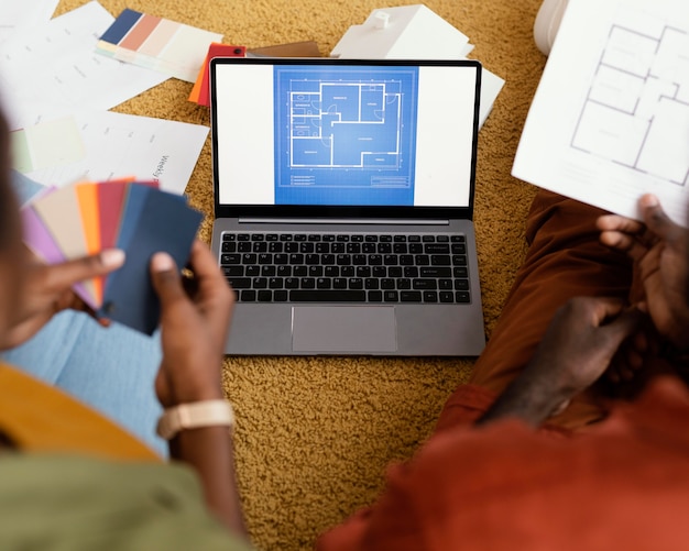 Free photo high angle of couple making plans to renovate house using color palette and laptop