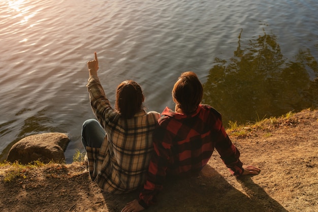 Бесплатное фото Пара под высоким углом сидит у озера